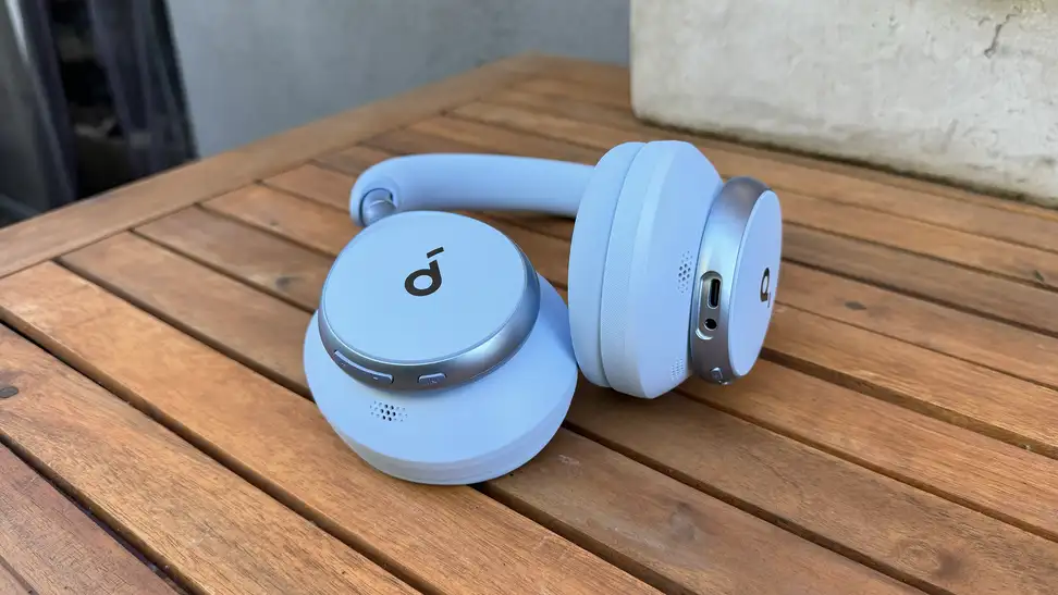The Anker Soundcore Space One in sky blue sitting on a wooden slat table.