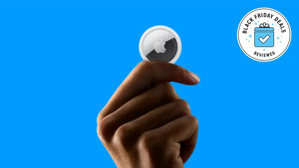A hand holding an Apple AirTag with the Black Friday Deals Reviewed badge in front of a colored background.