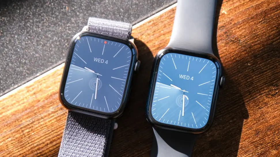 An Apple Watch Series 8 and 9 smartwatches side by side on top of wooden surface.