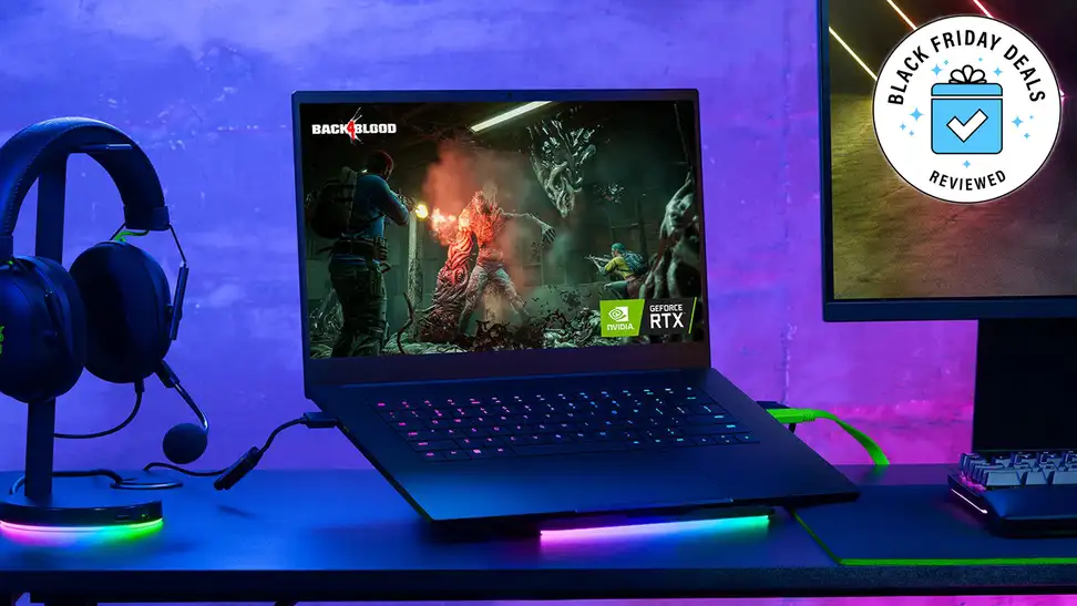 A Razer gaming laptop on a table between a headset and a monitor with the Black Friday Deals Reviewed badge.