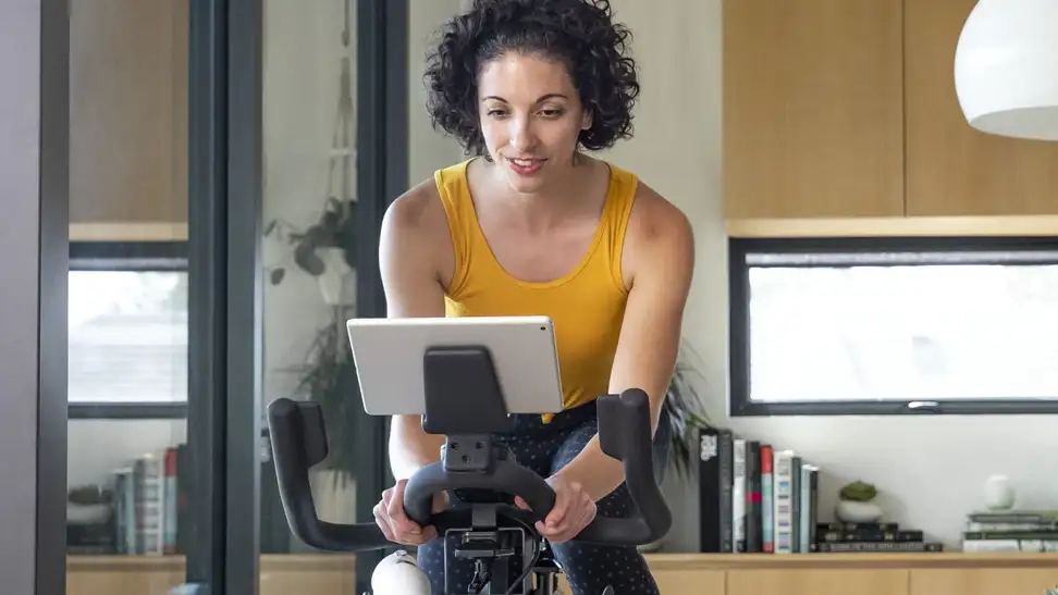 A woman using a Schwinn exercise bike in her home.