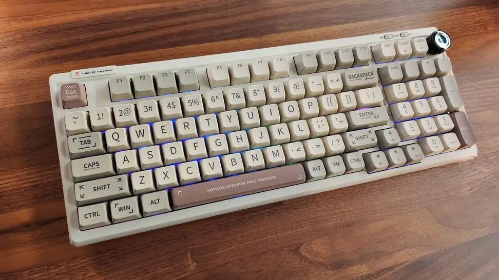 The Epomaker RT100 Mechanical Keyboard with the RGB keys on laying flat on a table.
