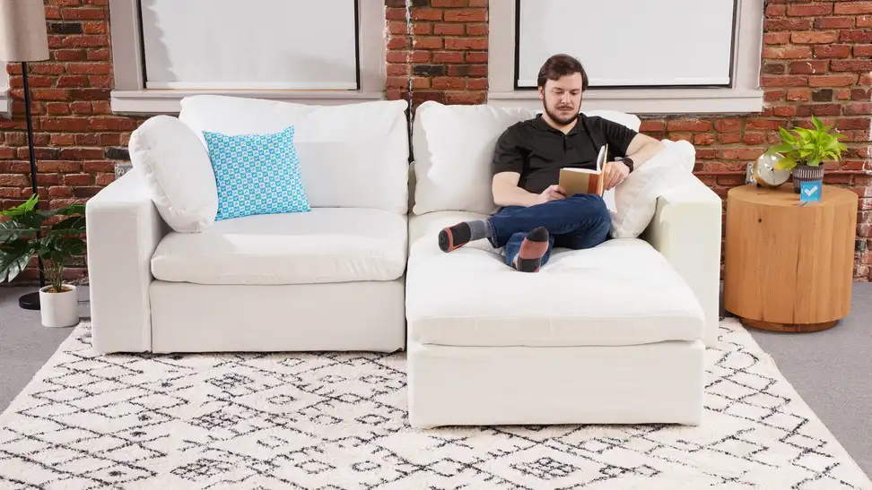 A front facing view of a 7th Avenue couch with a person sitting on the right side.