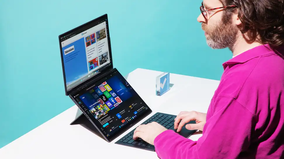 Person typing on the Asus Zenbook Duo laptop on top of a white desk.