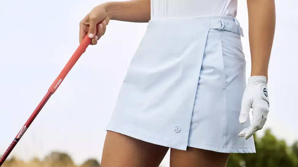 legs of female golfer wearing light blue golf skirt