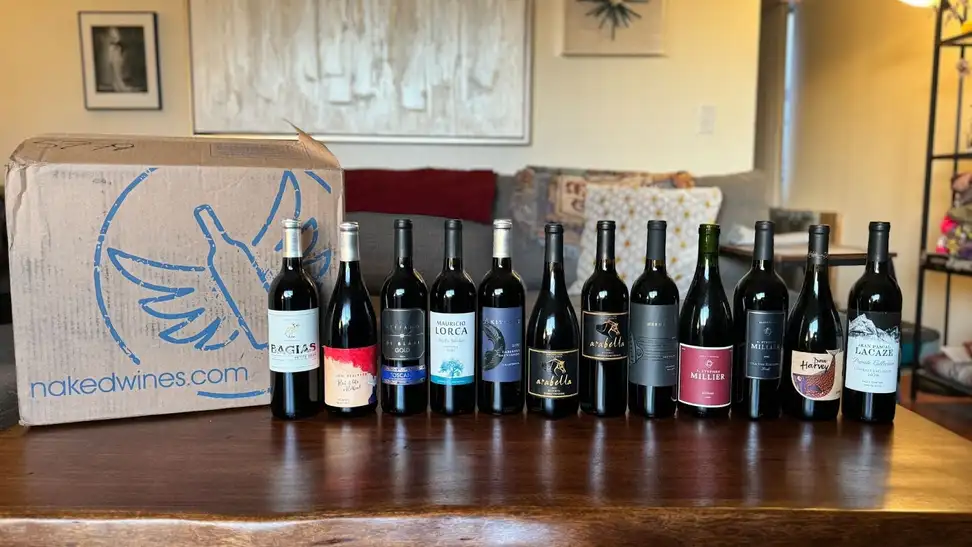 Naked Wines box beside 12 wine bottles beside it on a wooden table.