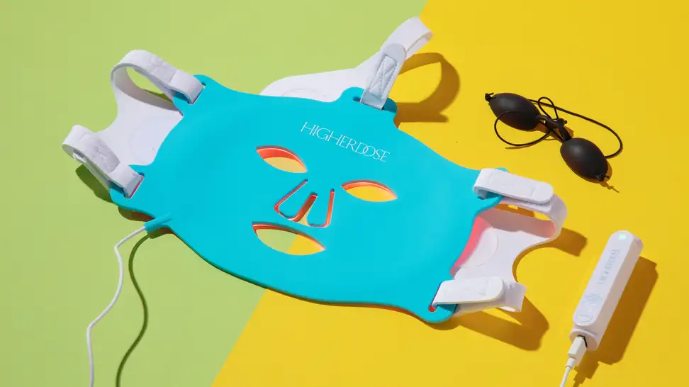 HigherDose Red Light Face Mask next to black eye goggles.