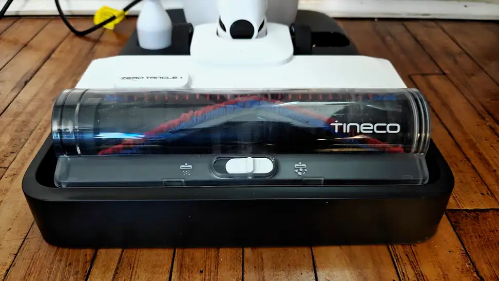 A Tineco vacuum head sits on its base on a wooden floor