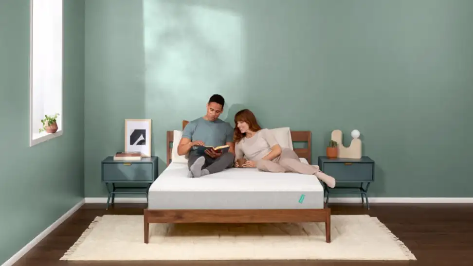A couple sitting on a Tuft and Needle mattress.