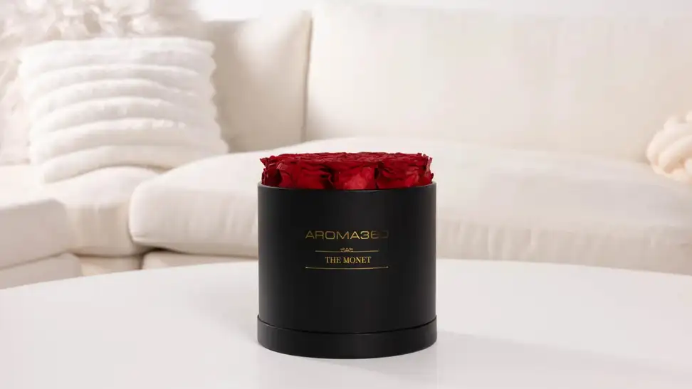 Aroma360 Monet floral diffuser sits on a coffee table in front of a white couch