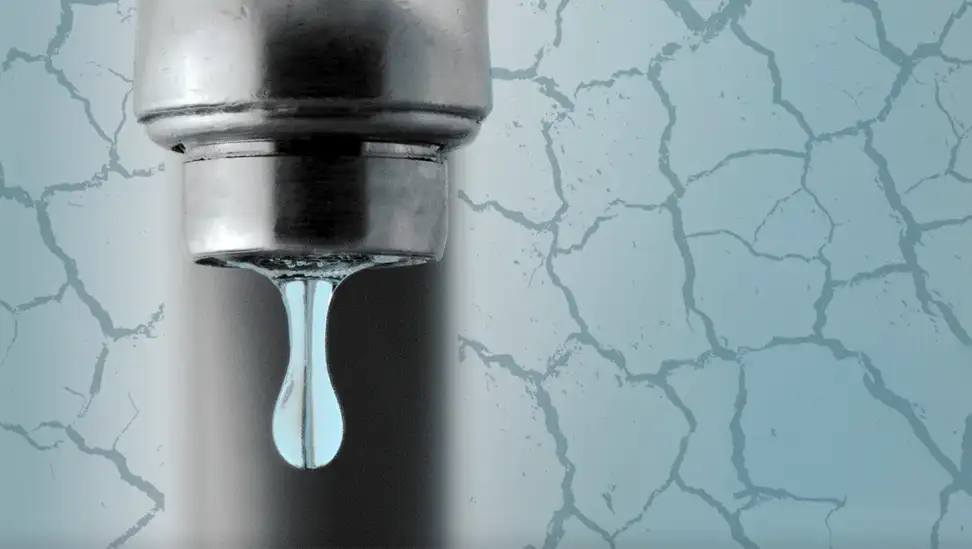 Pipe faucet dripping water surrounded by cracked ground.