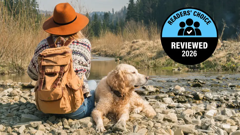Person sitting beside a dog by a rocky stream with a Reviewed Readers' Choice 2026 badge displayed.
