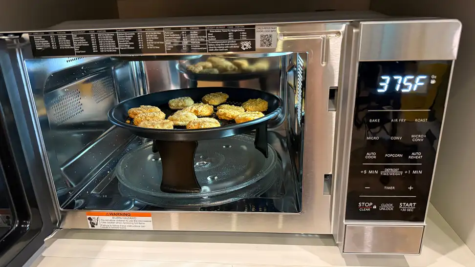 Stainless steel Sharp 900W Countertop Convection Microwave open and showing chicken nuggets inside.