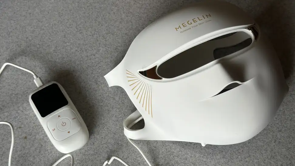 White Megelin LASER & LED mask and remote on grey surface.