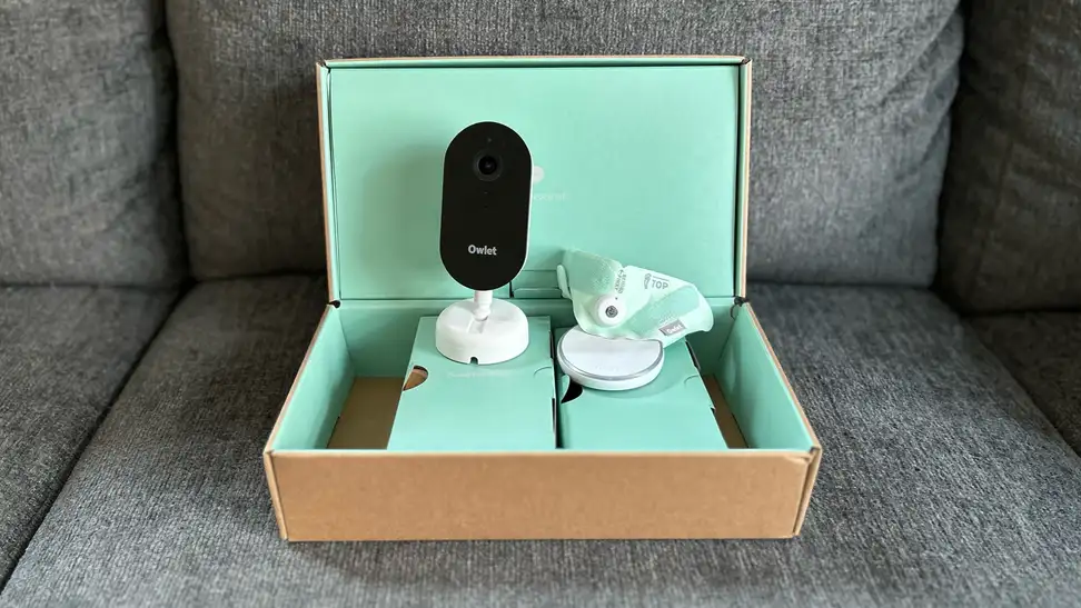 Owlet Dream Duo (Gen 3) components in mint green box sitting on a grey couch.