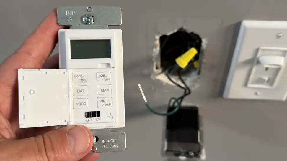 White Lider 7-Day Programmable Digital Timer Switch being installed with electrical wires seen hanging out of a grey wall.