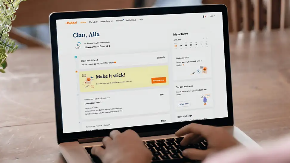 A laptop sits on a table showing Babbel's dashboard