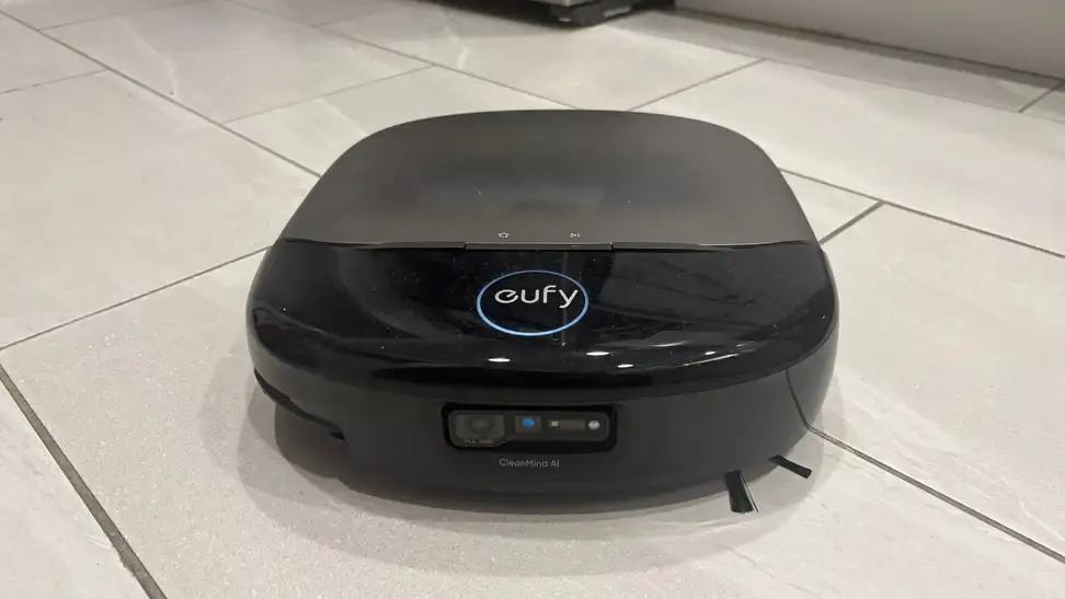 A black robot vacuum on a beige tile floor