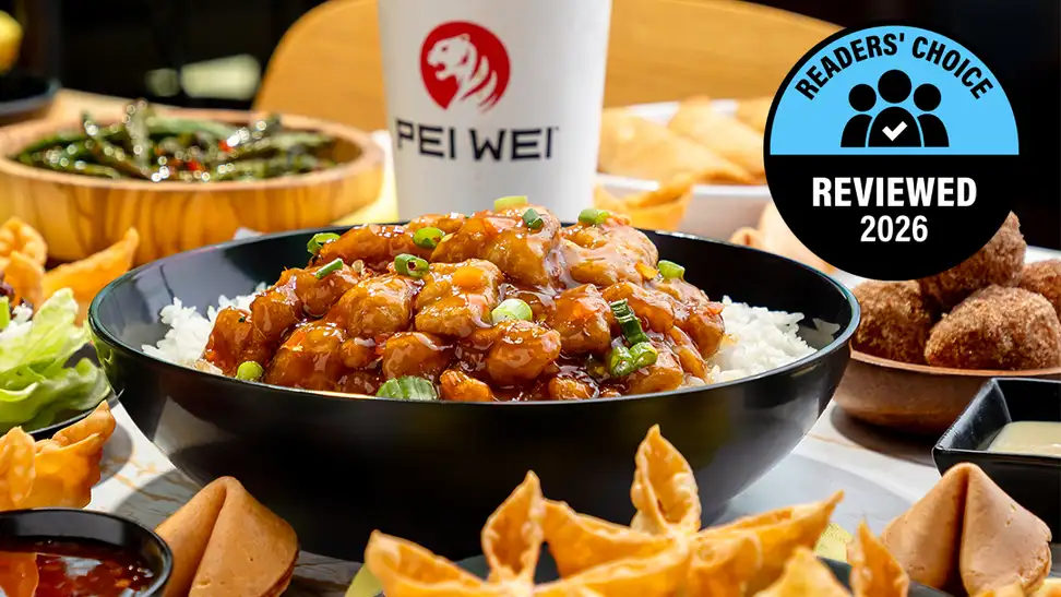 A close-up of a Pei Wei beef lo mein bowl with noodles, green beans, red peppers, and glazed beef on an orange branded background, with a Pei Wei cup visible and a Readers' Choice Reviewed 2026 badge.