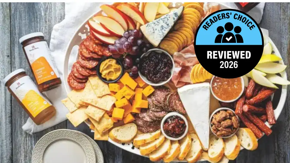 A deli platter with an assortment of cheese and fruit, with a "Readers' Choice Reviewed 2026 Nominee" badge.