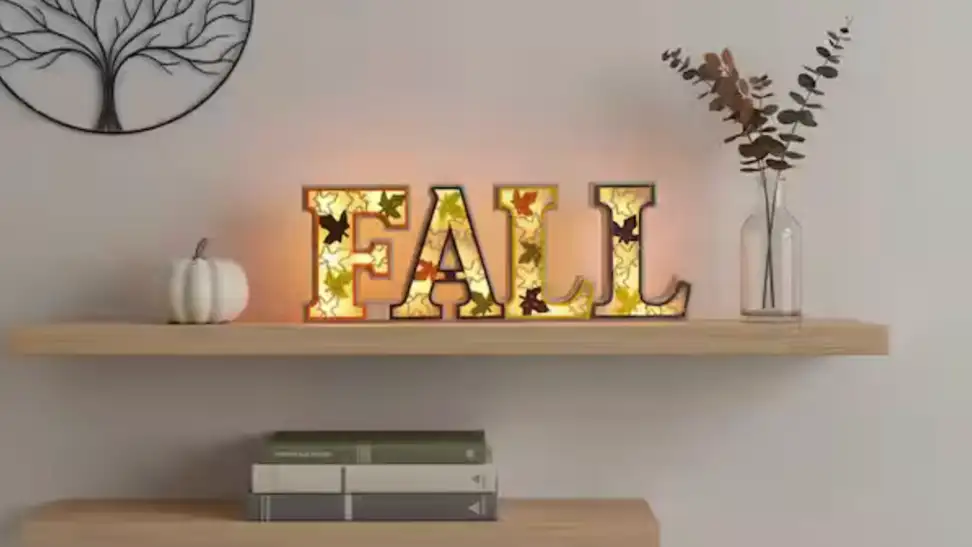 Home Depot Orange Rustic Lighted Fall Decor Sign LED on a wooden shelf hanging on a white wall.