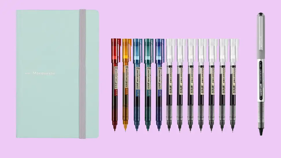 A mint-green notebook on the left is pictured with a variety of colorful Japanese pens.