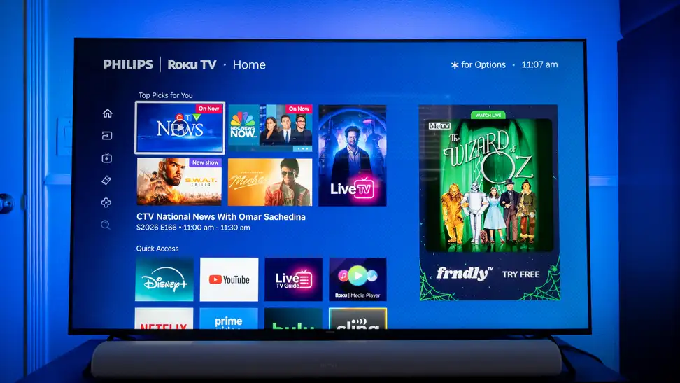 Philips Ambilight 7985 TV displaying Roku streaming options with blue illuminated light behind it.