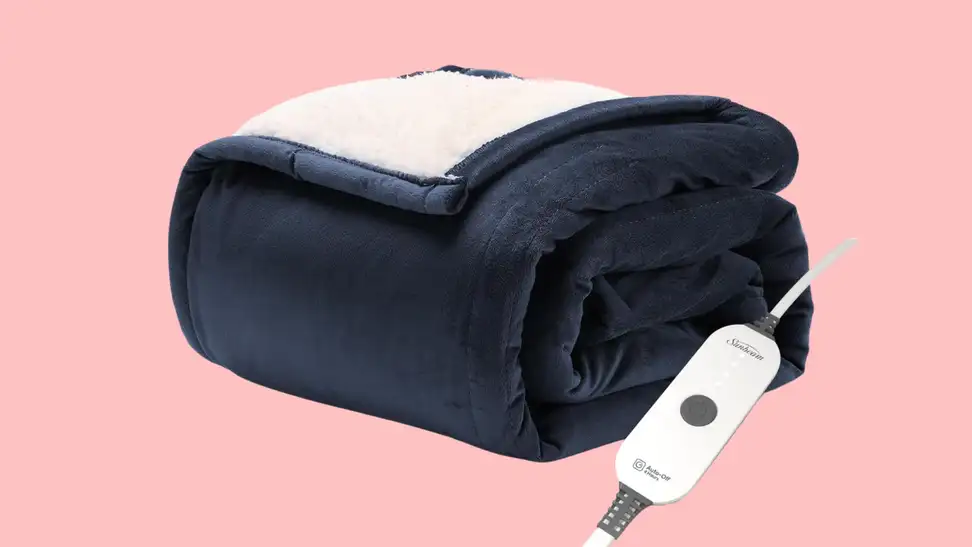 A folded blue electric blanket with a white sherpa lining is shown against a pink background.