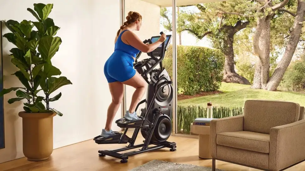 a woman in blue athletic gear uses a Bowflex in her living room
