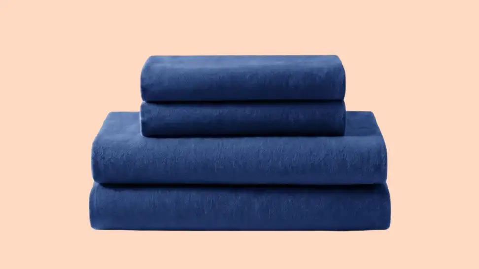 Navy blue folded sheet set against a peach-colored background.