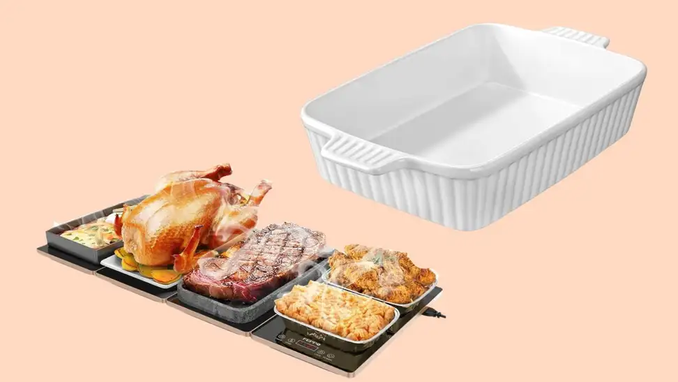 A warming plate covered with dishes of food and a white ceramic baking dish against a peach-colored background.