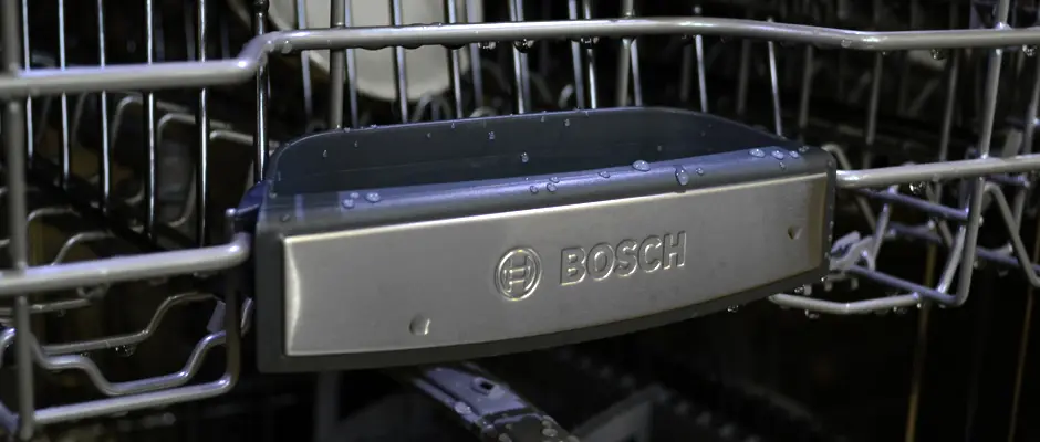 A close-up of the front of a Bosch dishwasher's top rack, which has the Bosch logo on it.