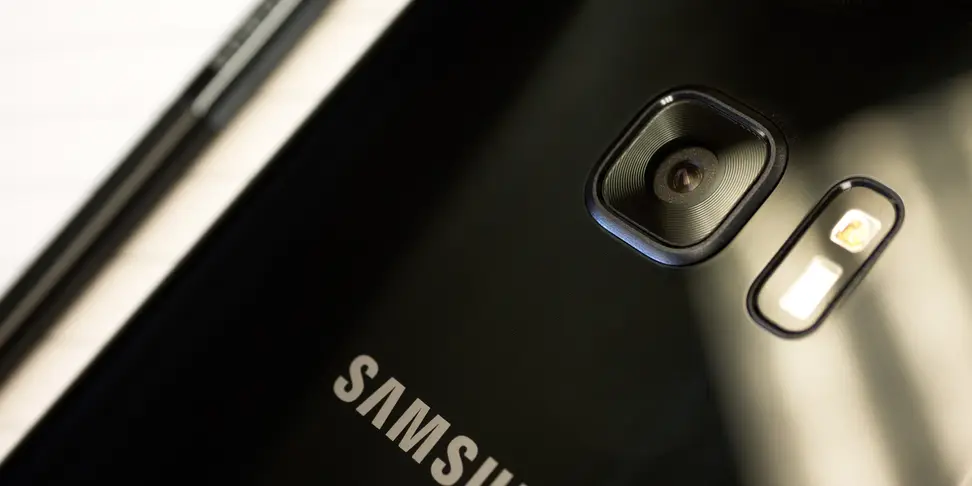 Close-up of a black Samsung smartphone with a built-in camera lens and flash bulb.