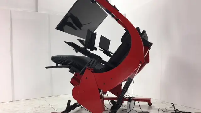 Red and black ergonomic workstation with large monitor tilted to a reclined position