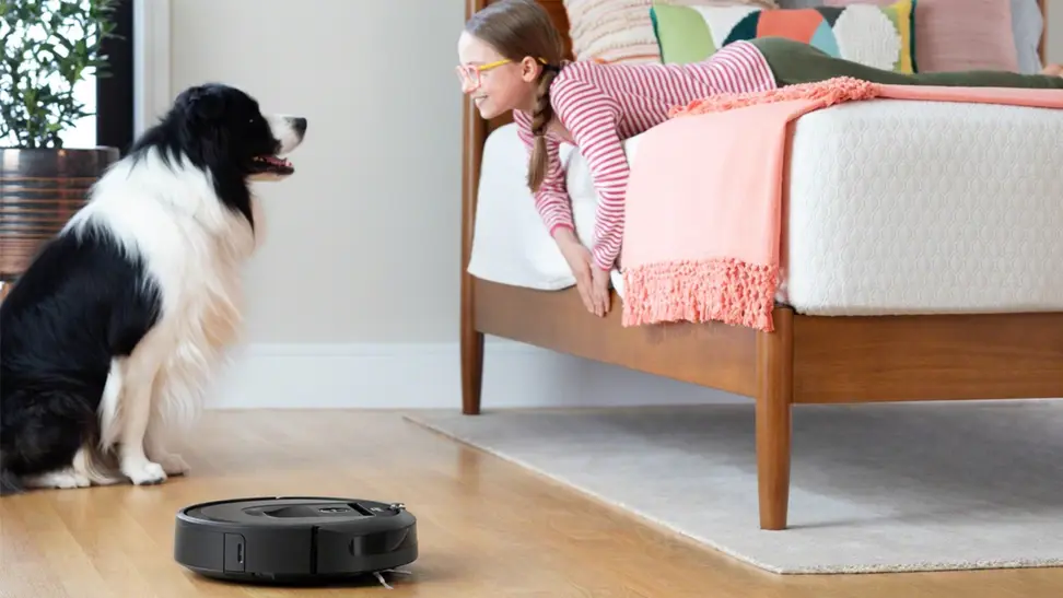 Dog and girl looking at each other with a robot vacuum on the floor
