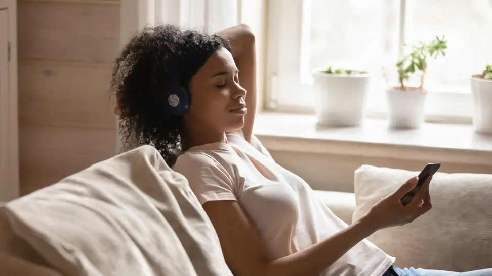 Woman sits on her couch meditating