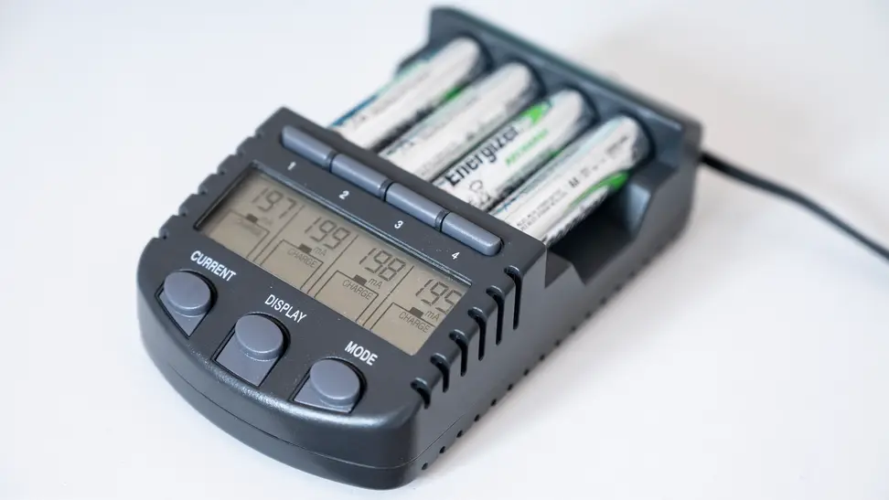 Close-up of a gray rechargeable battery pack with four white Energizer AA batteries inserted.