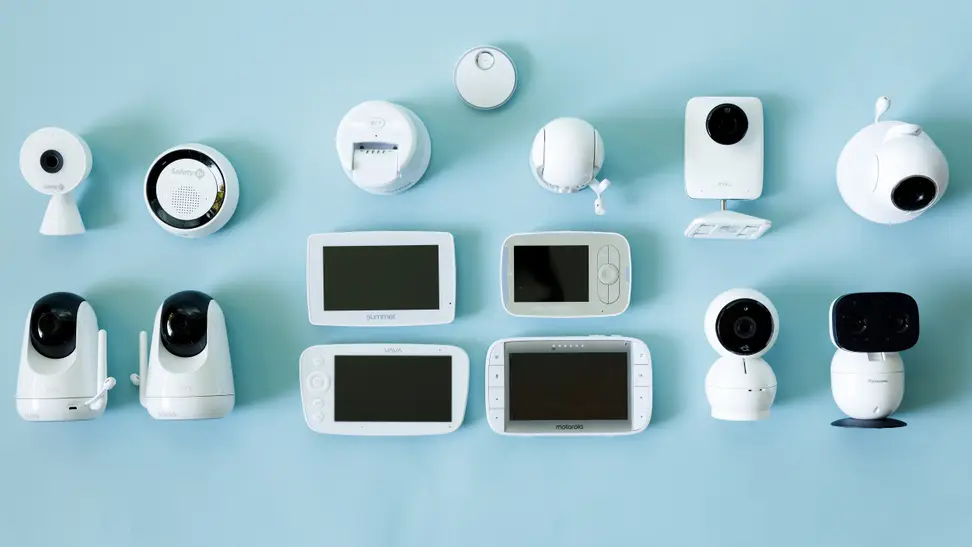 Many baby monitors with video screens lay on an aqua background