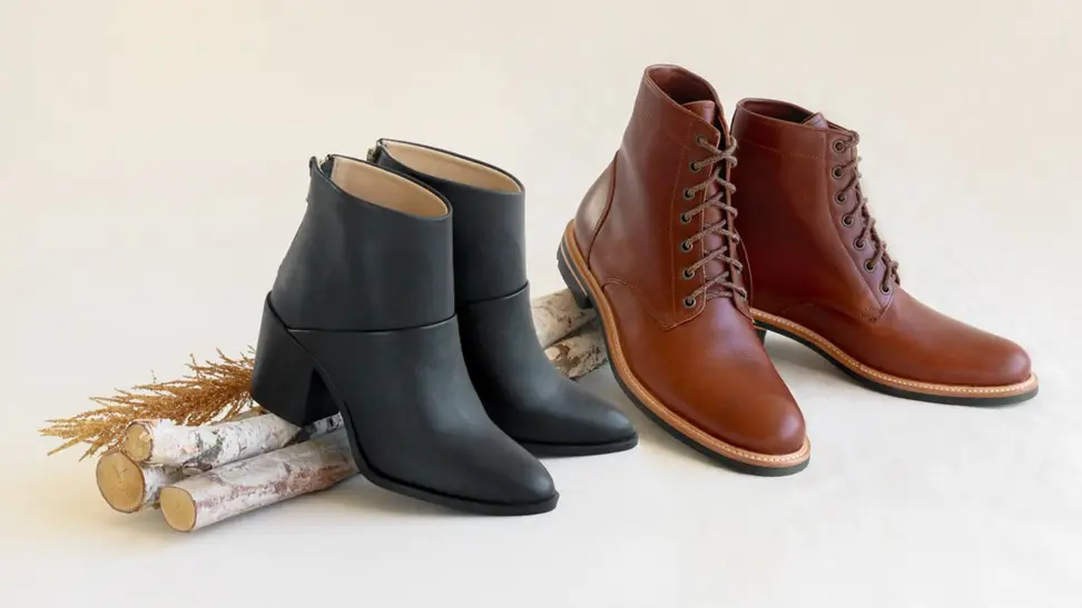 A black pair of boots next to a brown pair of boots on a stick.