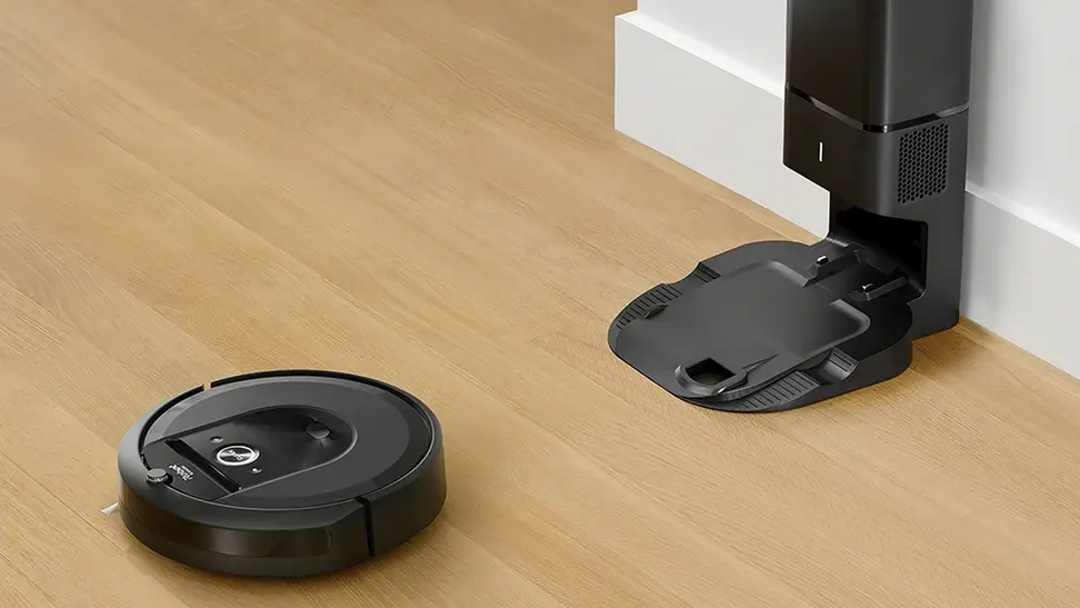 A Roomba on the floor near its dirt removal station.