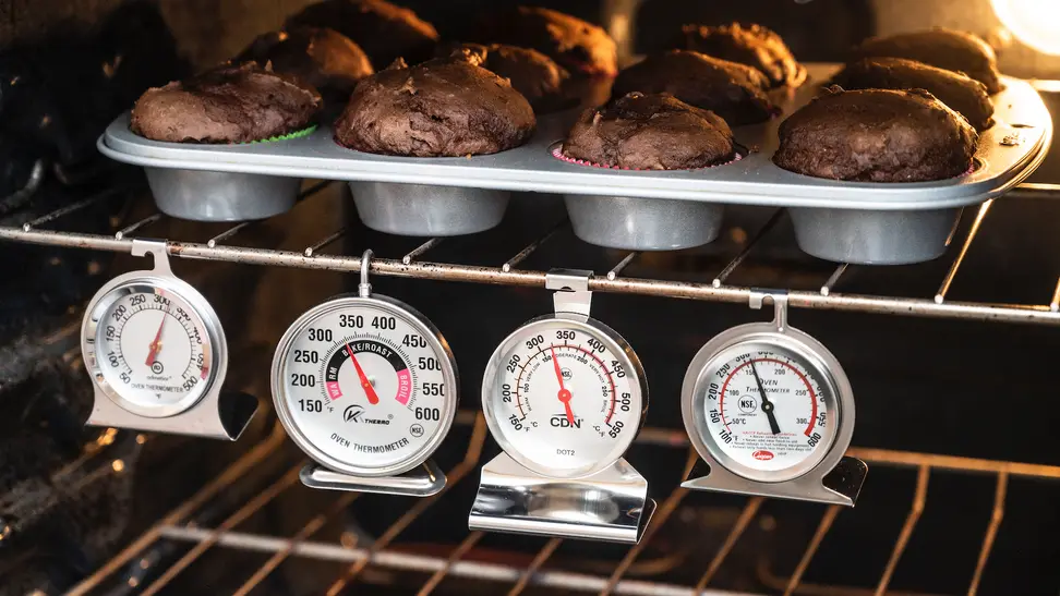 Four of the best oven thermometers Reviewed tested hang inside an oven under a tray of chocolate muffins.