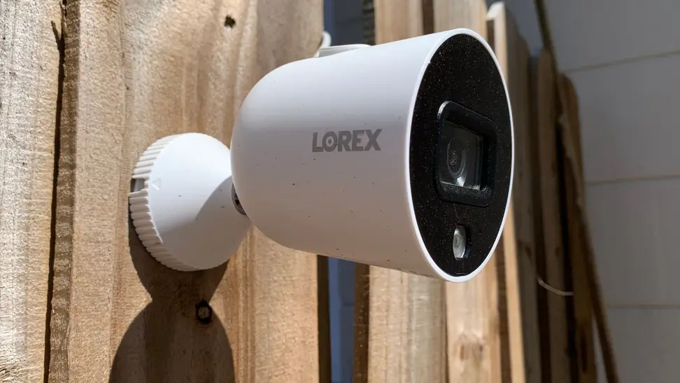 The Lorex Smart Indoor/Outdoor 1080p WiFi Camera hangs on a wood fence.