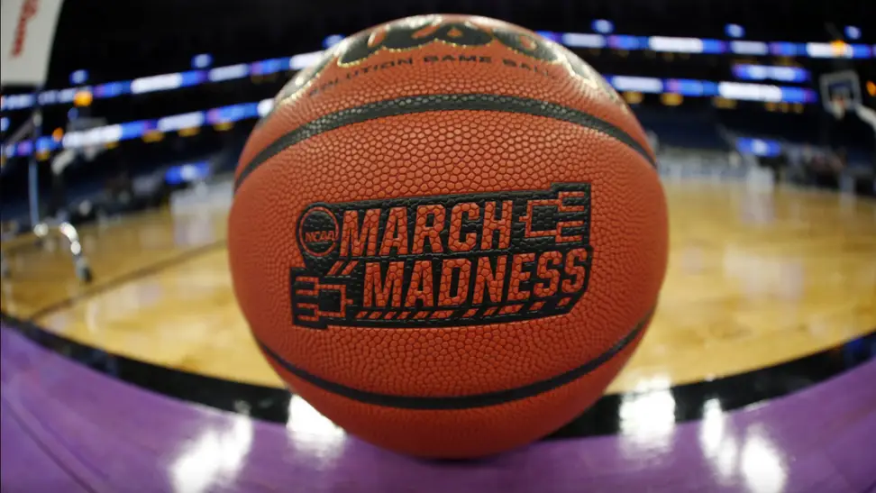 March Madness imprinted on a basketball on a basketball court