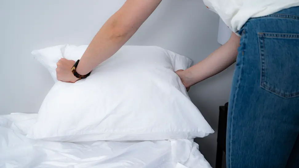 a woman holds the edges of a pillow in a pillow protector