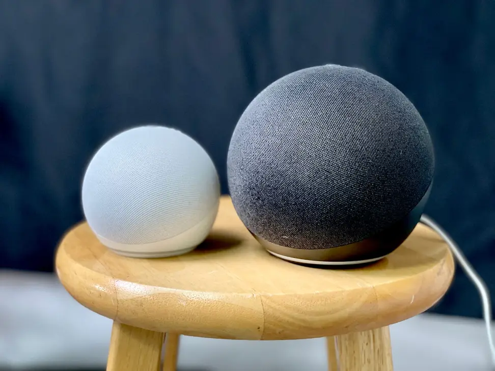 Two Echo Dot speakers on a side table.