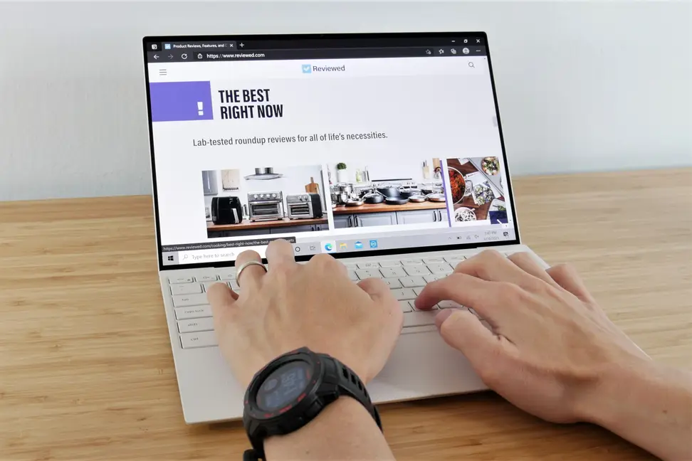 Hands resting on top of an open laptop.