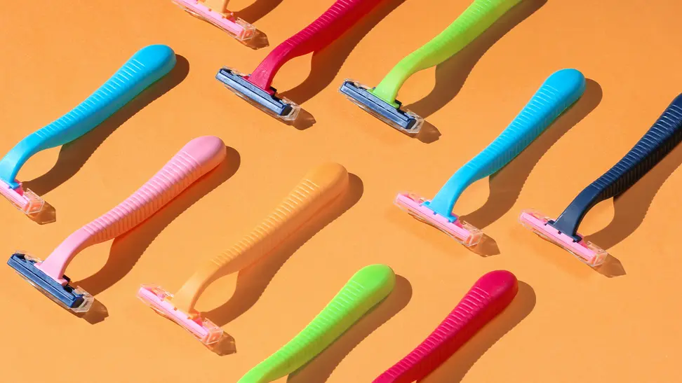 Two rows of colorful razors lay atop an orange background.