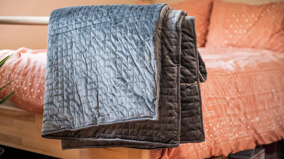 the gravity blanket hangs on the end of a bed