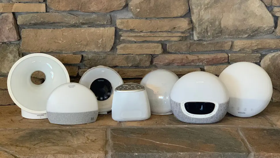 Seven sunrise alarm clocks lined up next to each other on a neutral stone background
