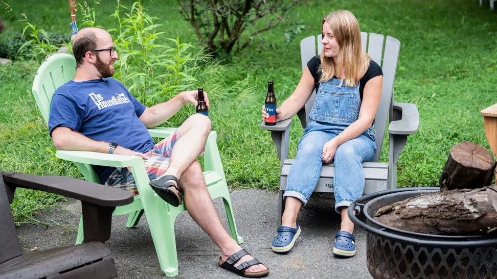 Man and woman sitting in adirondack chairs talking.